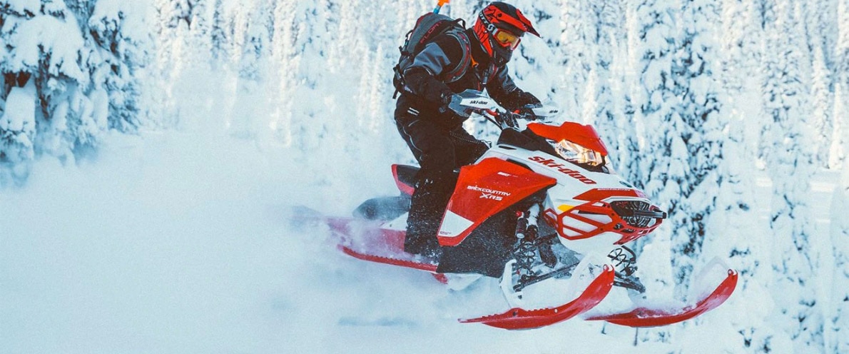  Človek s svojim Ski-Doo Backcountryjem skače skozi sneg