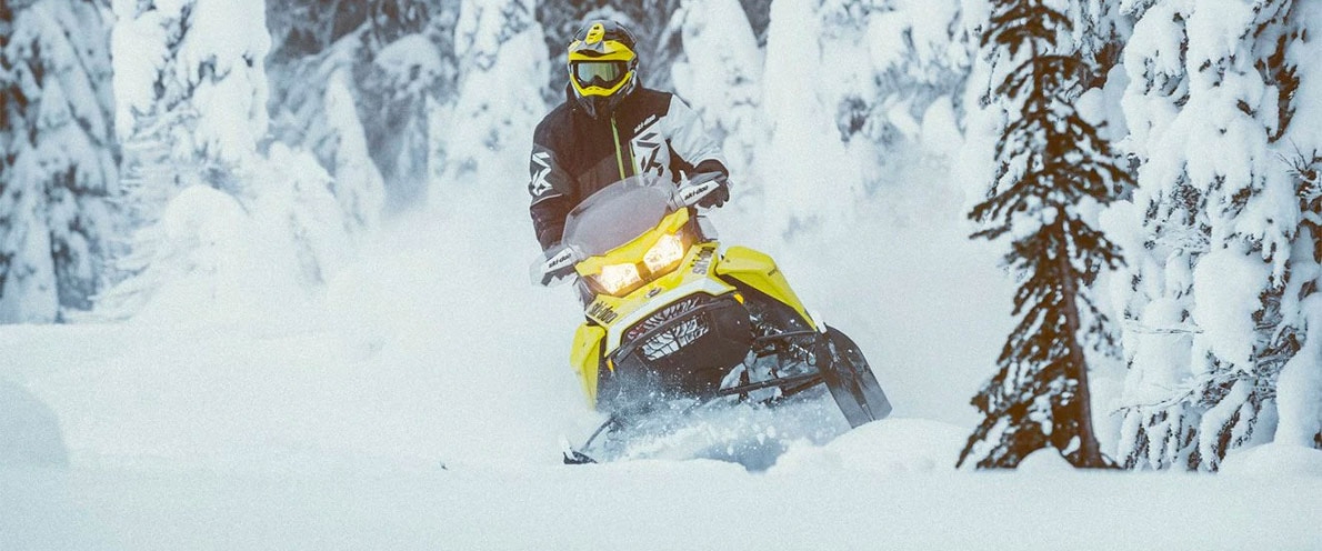 Muž driftující sněhem na sněžném skútru Ski-Doo