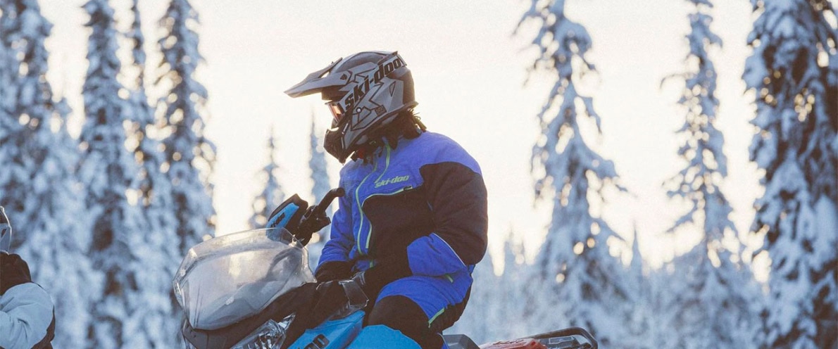 Man talking with an off-screen individual while sitting on his snowmobile