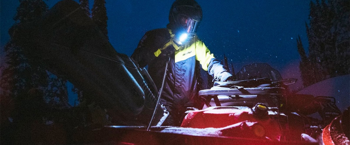 Man looking through his Ski-Doo accessories using a pocket flashlight