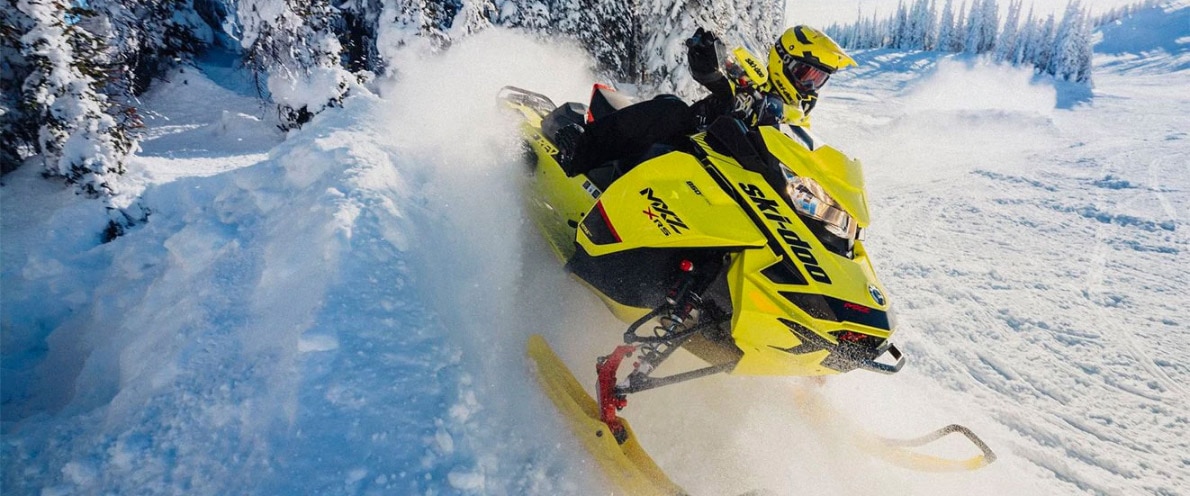 Muž driftující na sněhem se svým sněžným skútrem Ski-Doo MXZ