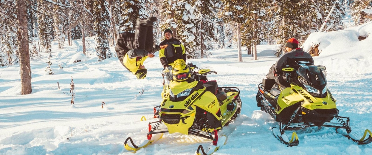 Man doing a back-flip near his Ski-Doo MXZ