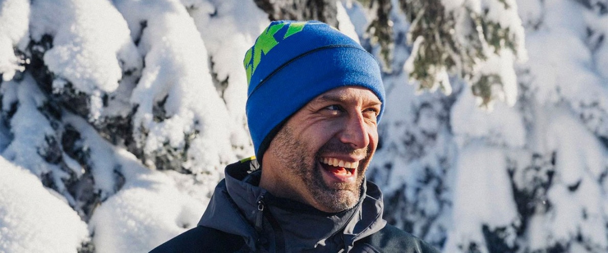 Obrázek muže usmívajícího se u zasněženého lesa