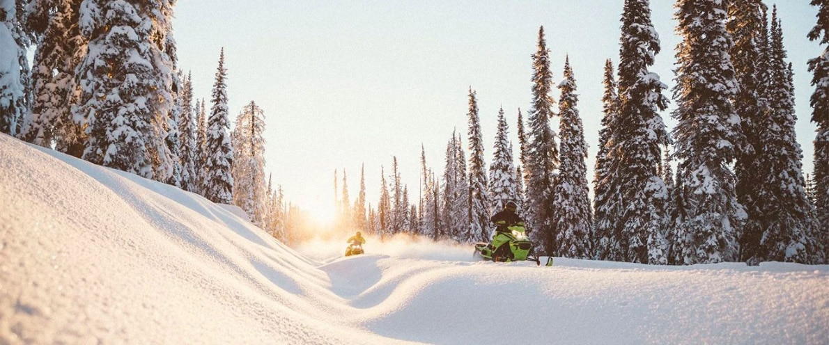 Two men driving a Ski-Doo Renegade through a snowy trail