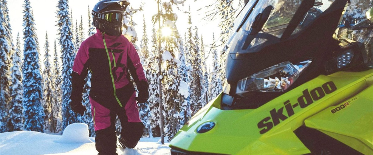 Osoba procházející kolem sněžného skútru Ski-Doo Renegade