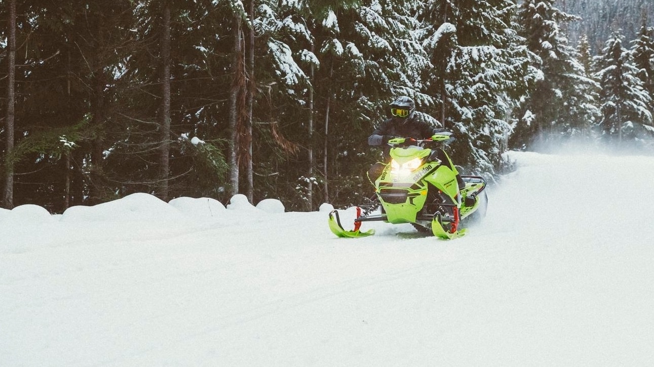 Muž driftující sněhem se svým sněžným skútrem Ski-Doo Renegade