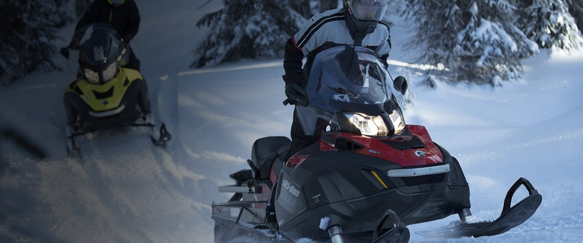 Close-up of two people driving in a snowy forest trail