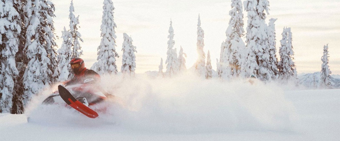 Man drifting through deep snow on his snowmobile