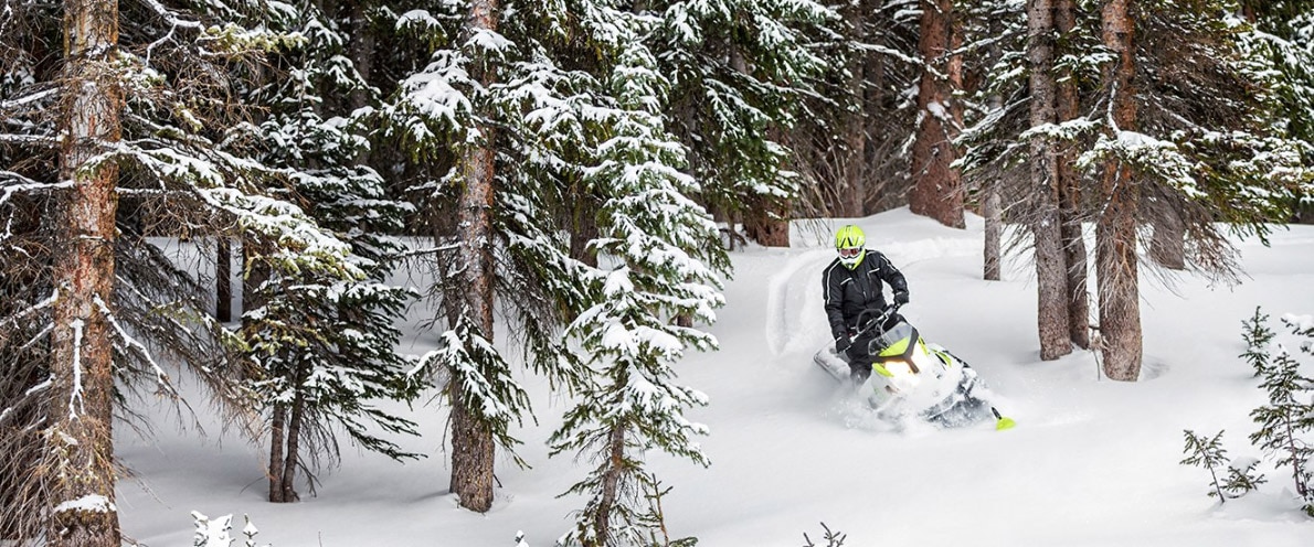 Muž jedoucí zasněženou cestou z kopce na skútru Ski-Doo Tundra