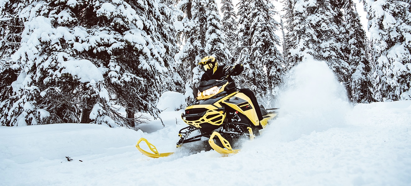 Man driving a Ski-Doo Renegade through a snowy forest trail