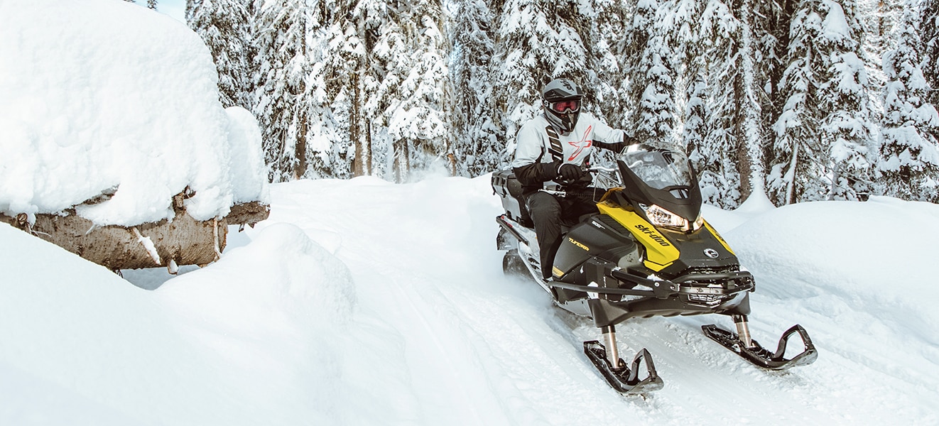 Muž jedoucí na sněžném skútru Ski-Doo Tundra po zasněžené stezce