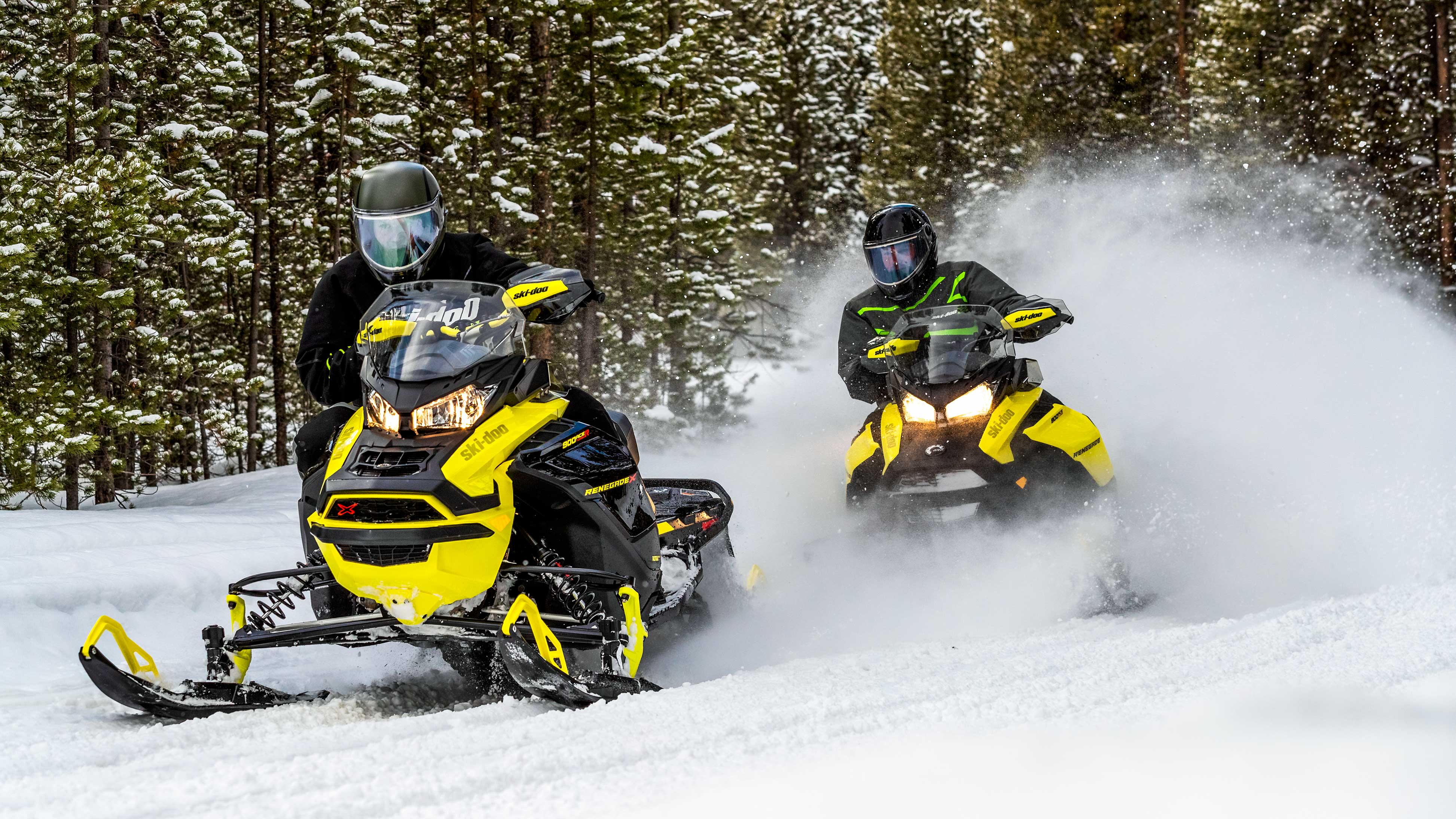 Ski-Doo Renegade'lerini bir patikada süren biniciler