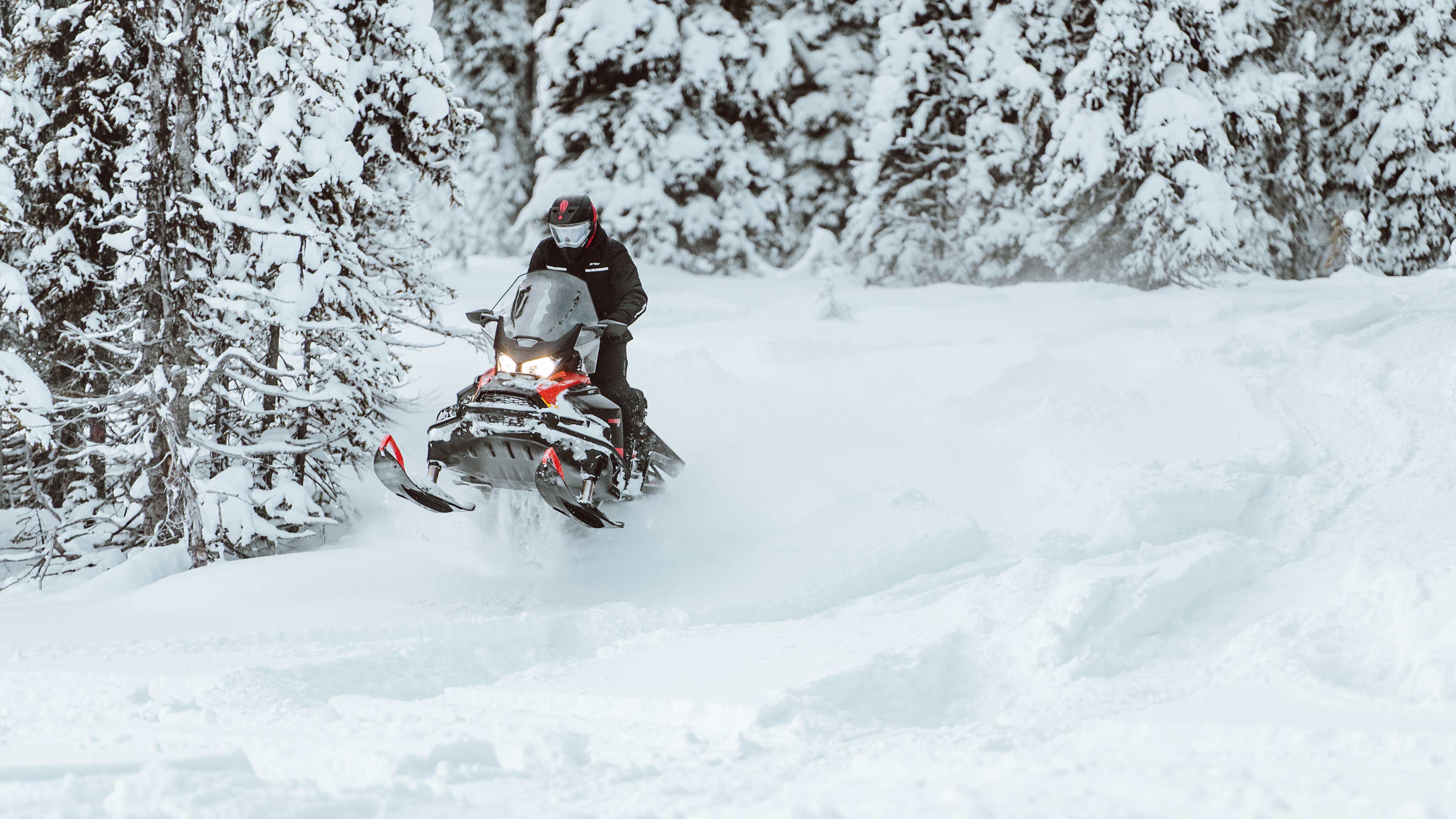  Moški vozi sani Ski-Doo Skandic v globokem snegu