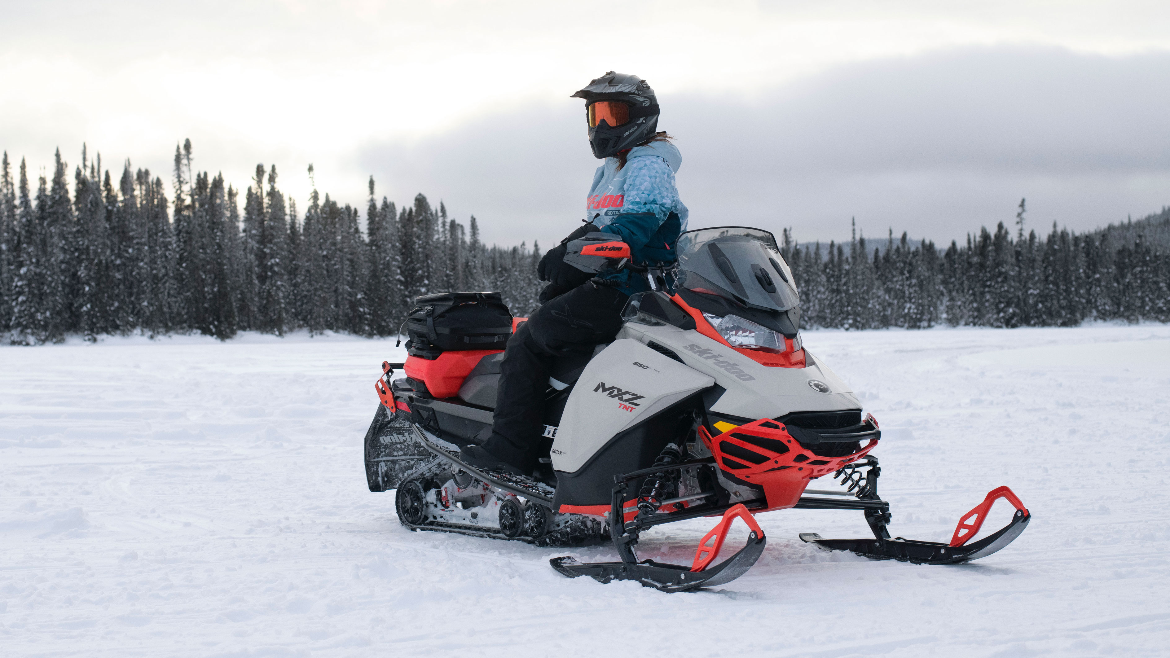 Жена - возач на Ski-Doo моторна санка, која ужива во погледот седната на својата санка