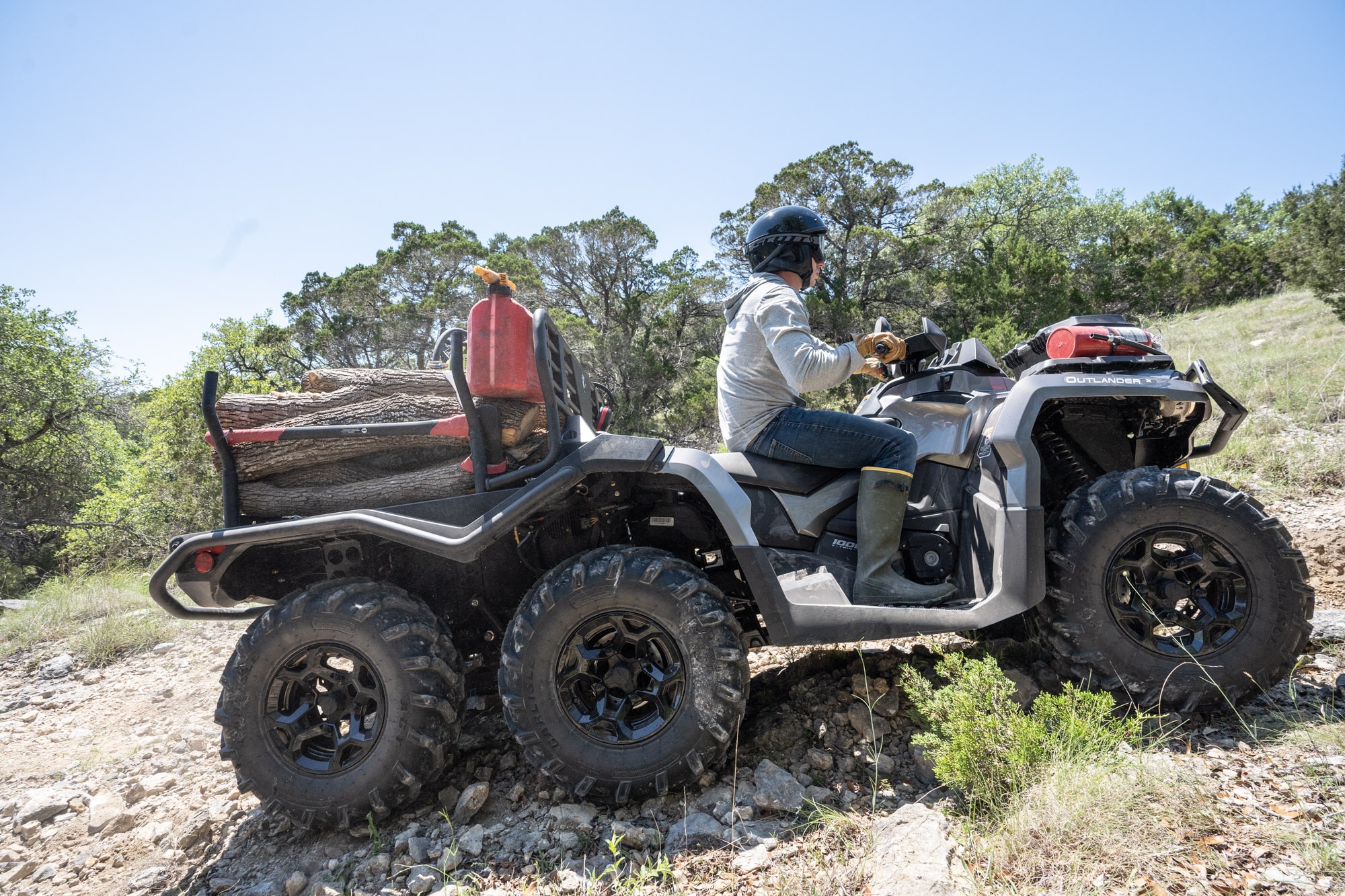 An Outlander PRO ATV with a trailer carrying wood driving away