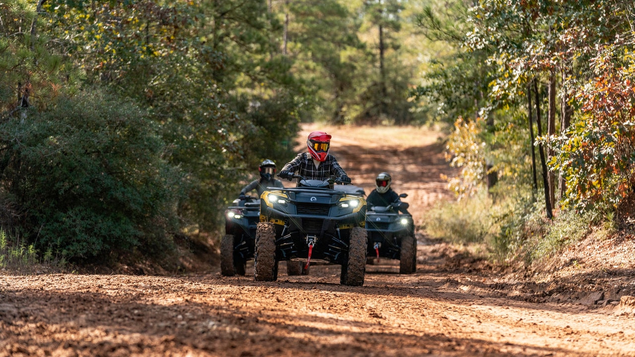 Traja jazdci ATV idú za sebou na trali