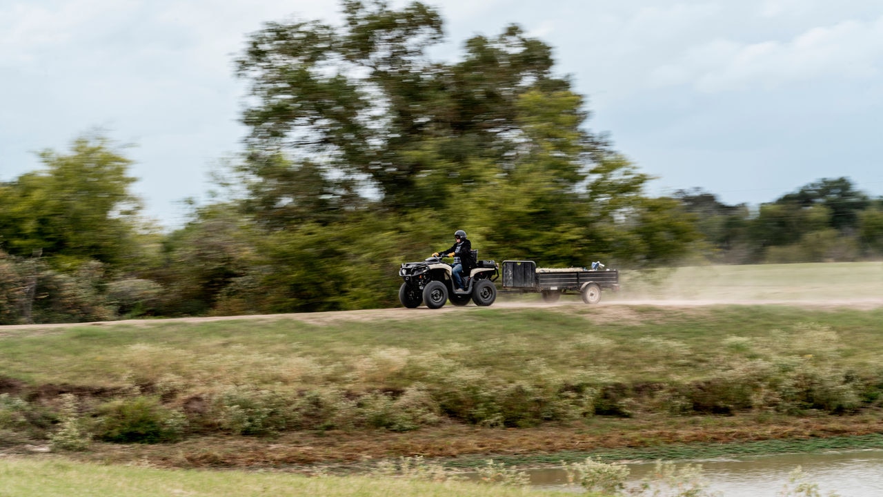 An Outlander PRO ATV with a trailer carrying wood driving away