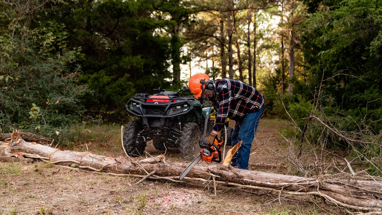 Muž používa motorovú pílu pred Can-Am ATV