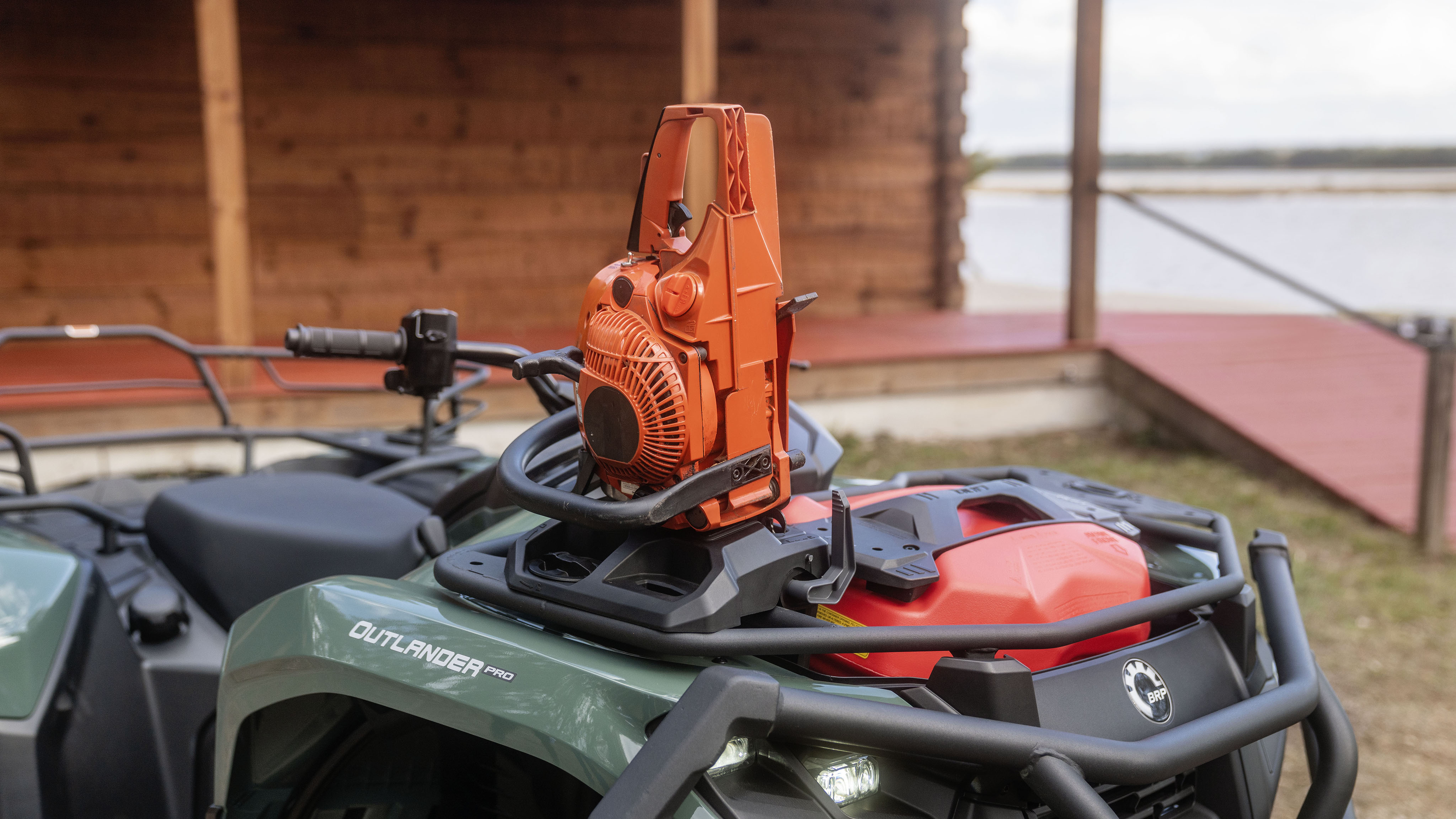 A Can-Am Outlander PRO XU holding a chainsaw in the dedicated slot, equipped with a LinQ Jerry can and bumpers