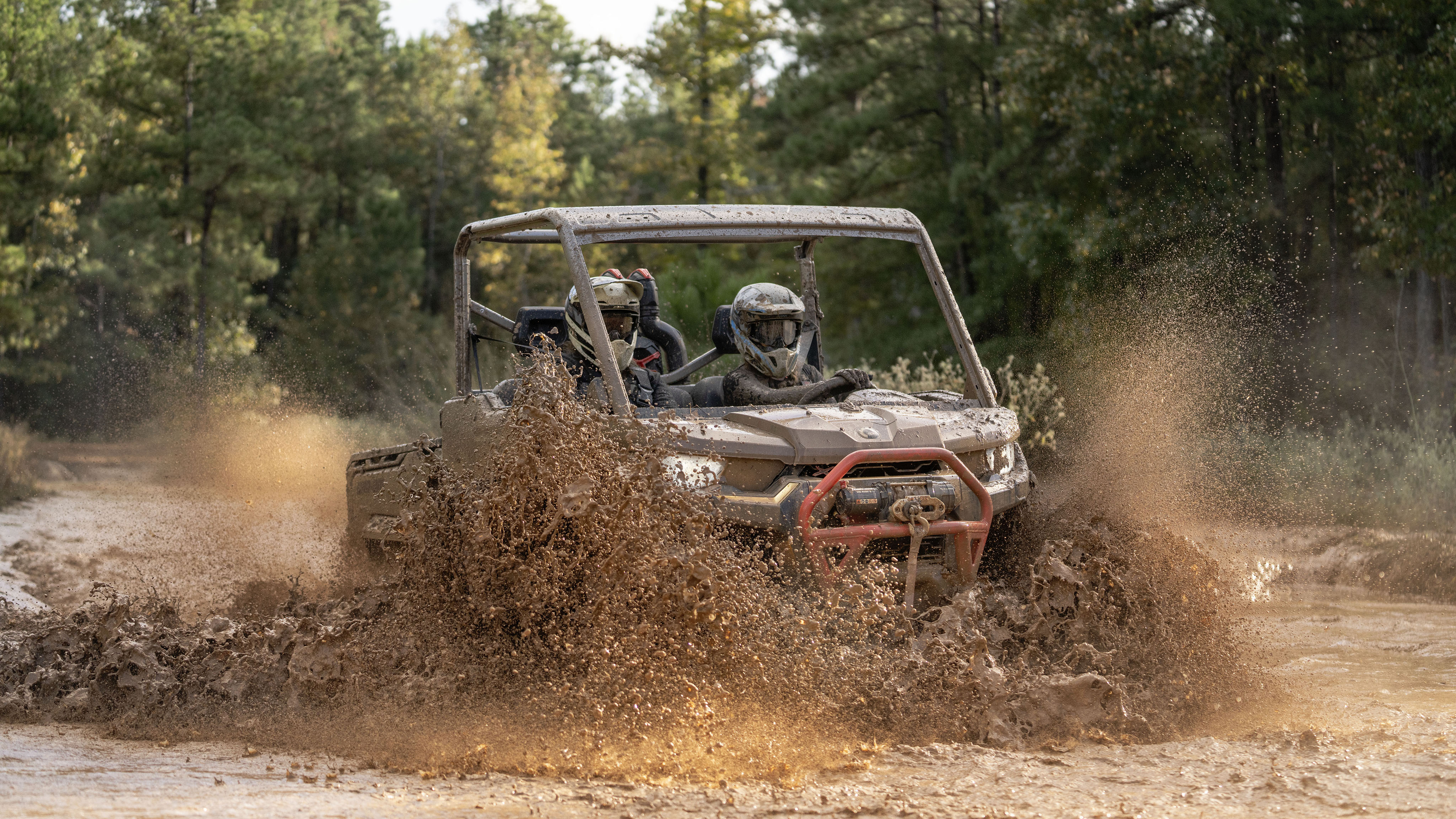 People riding their side-by-sides in a mudhole