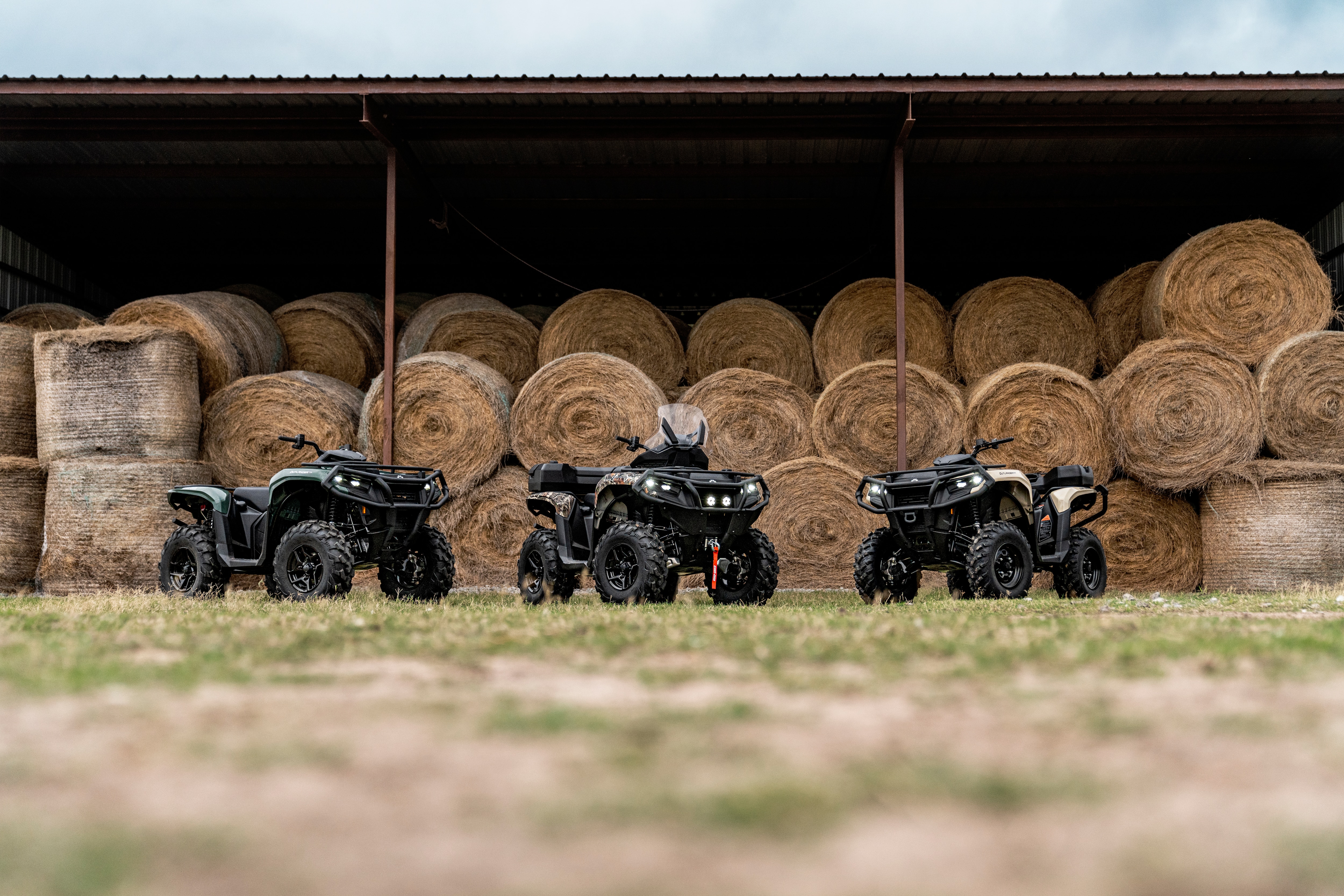 Three Outlanders in a field in front of bales of hay