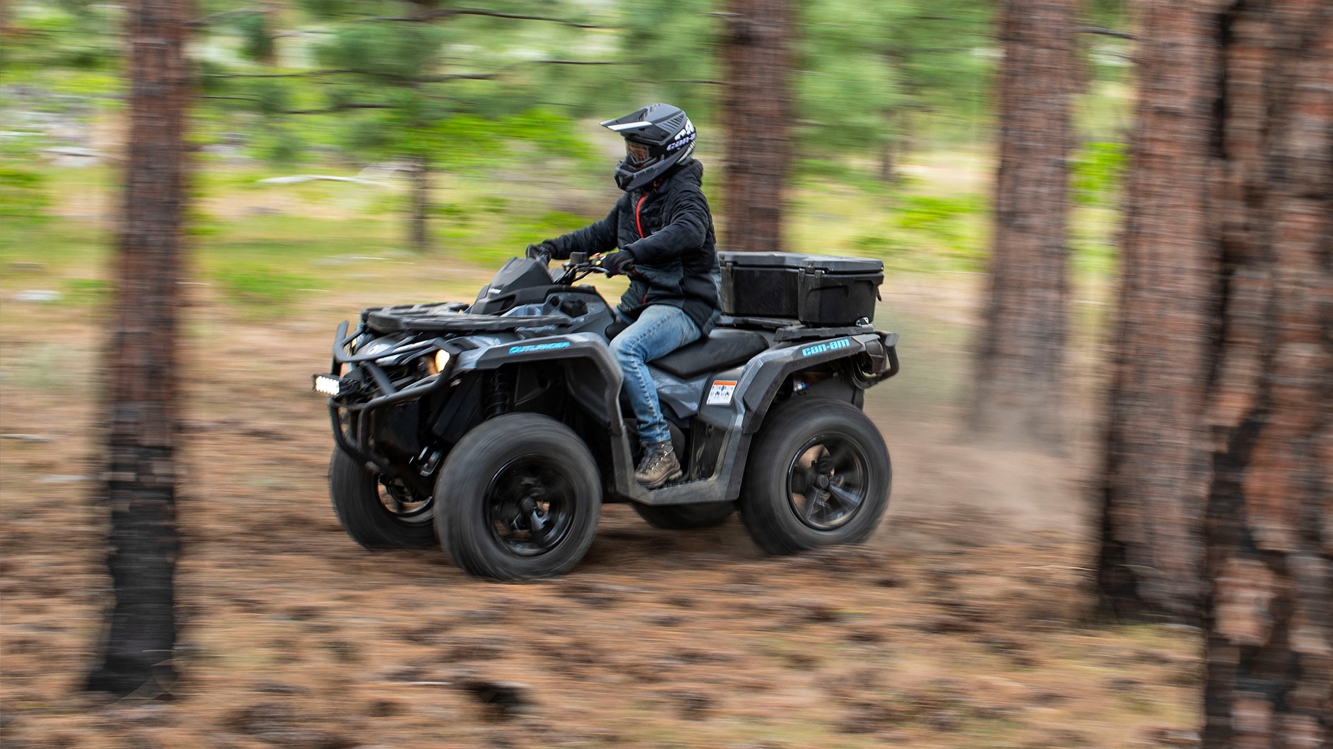 Rider going full speed through a forest on a Can-Am Outlander all terrain vehicle