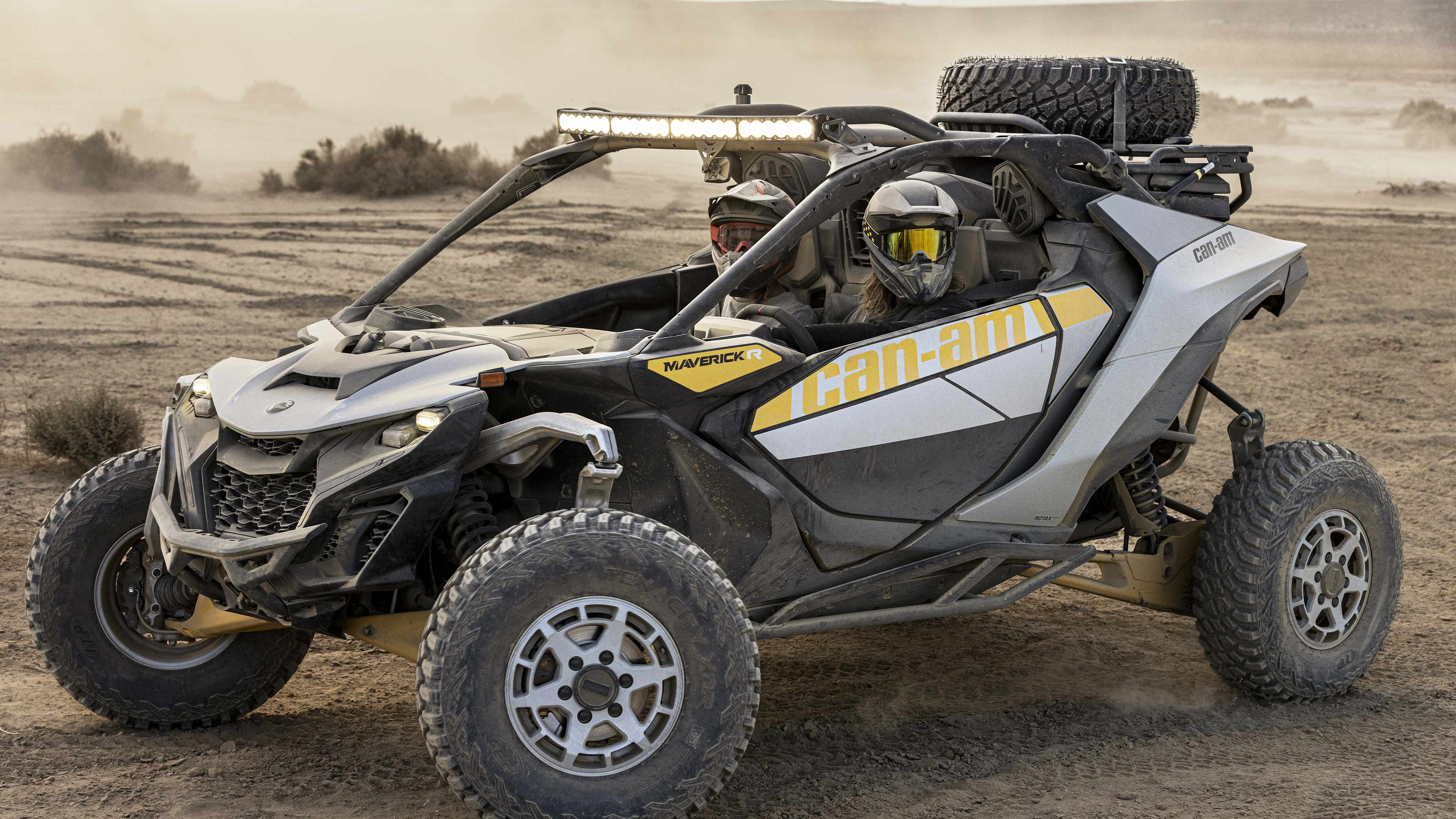 A man in the desert with his Can-Am Maverick R SxS in the background