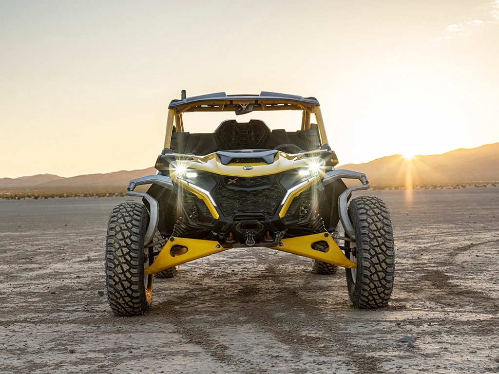 A Can-Am Maverick R SxS parked with its lights on in the desert