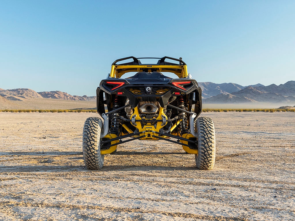 A close-up of the back and shock absorbers of a Can-Am Maverick R parked in a desert