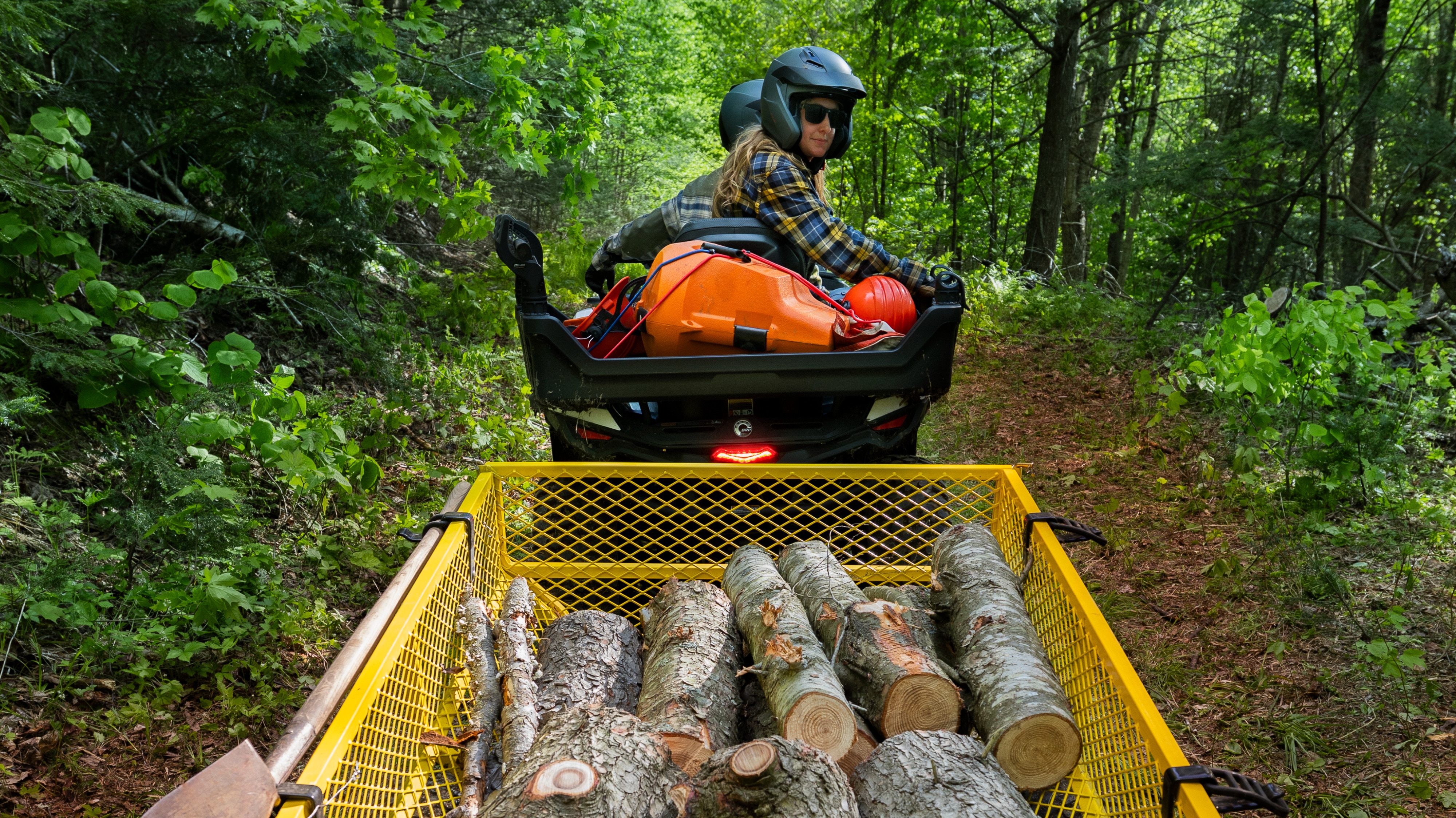 A couple hauling logs with their Can-Am Outlander Electric ATV