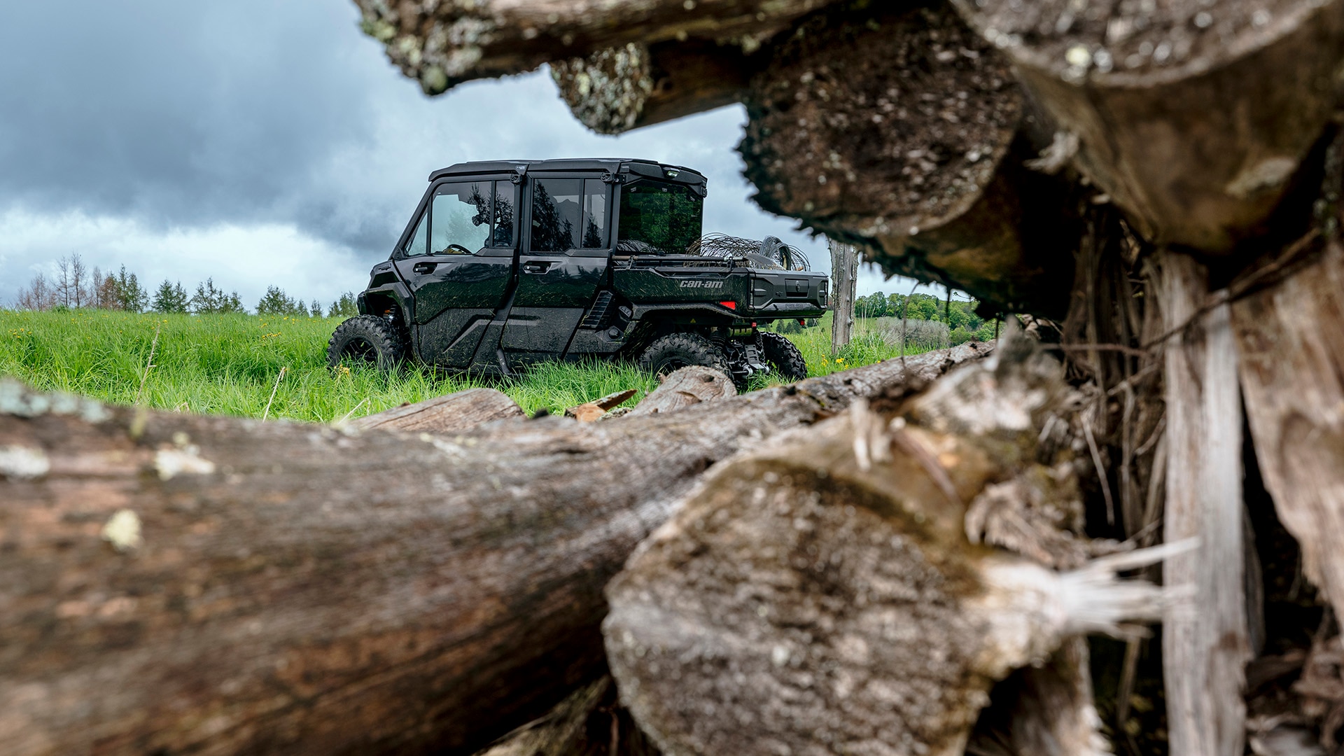2026 Can-Am Traxter HD11 Max in the lawn, near several logs