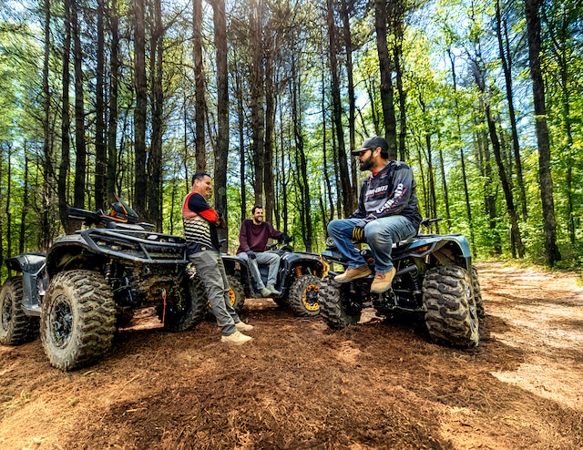 Several drivers taking a break on their 2026 Can-Am Outlander all-terrain vehicle in the forest