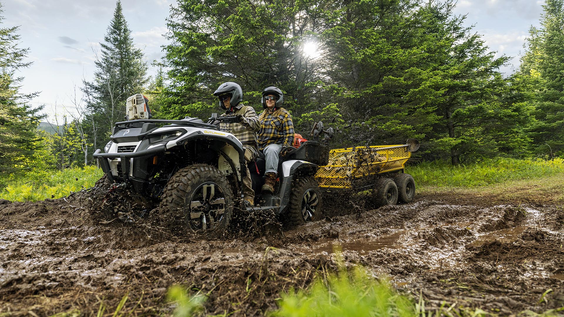 A couple on an all-new Can-Am Outlander Electric 2026 designed for work, passing through mud