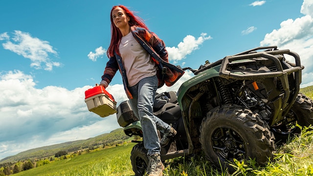 A woman who has just steeped out from her 2026 Can-Am Outlander MAX PRO XU HD7 on her land