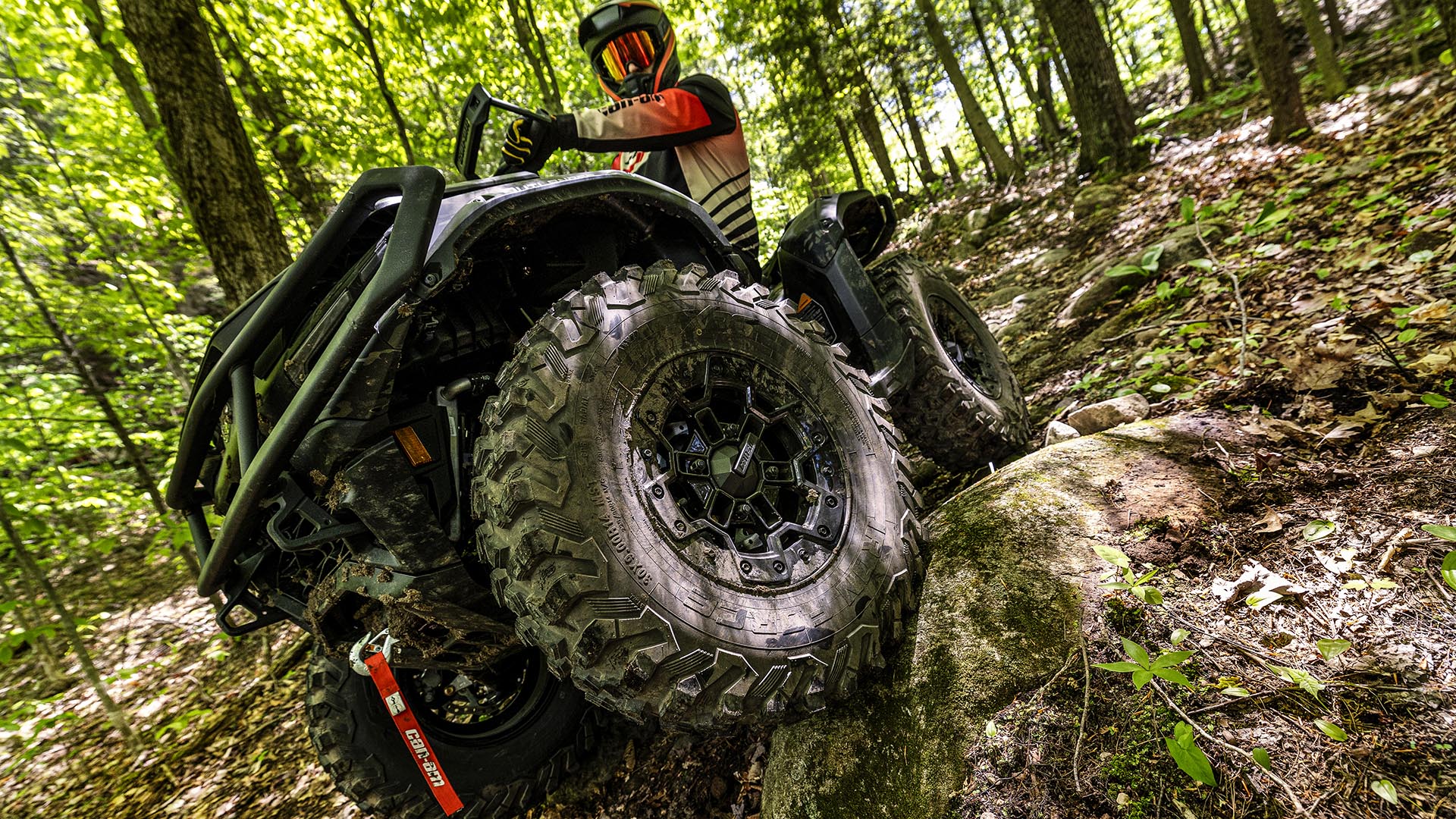 Can-Am Outlander ATV riding through a wet forest