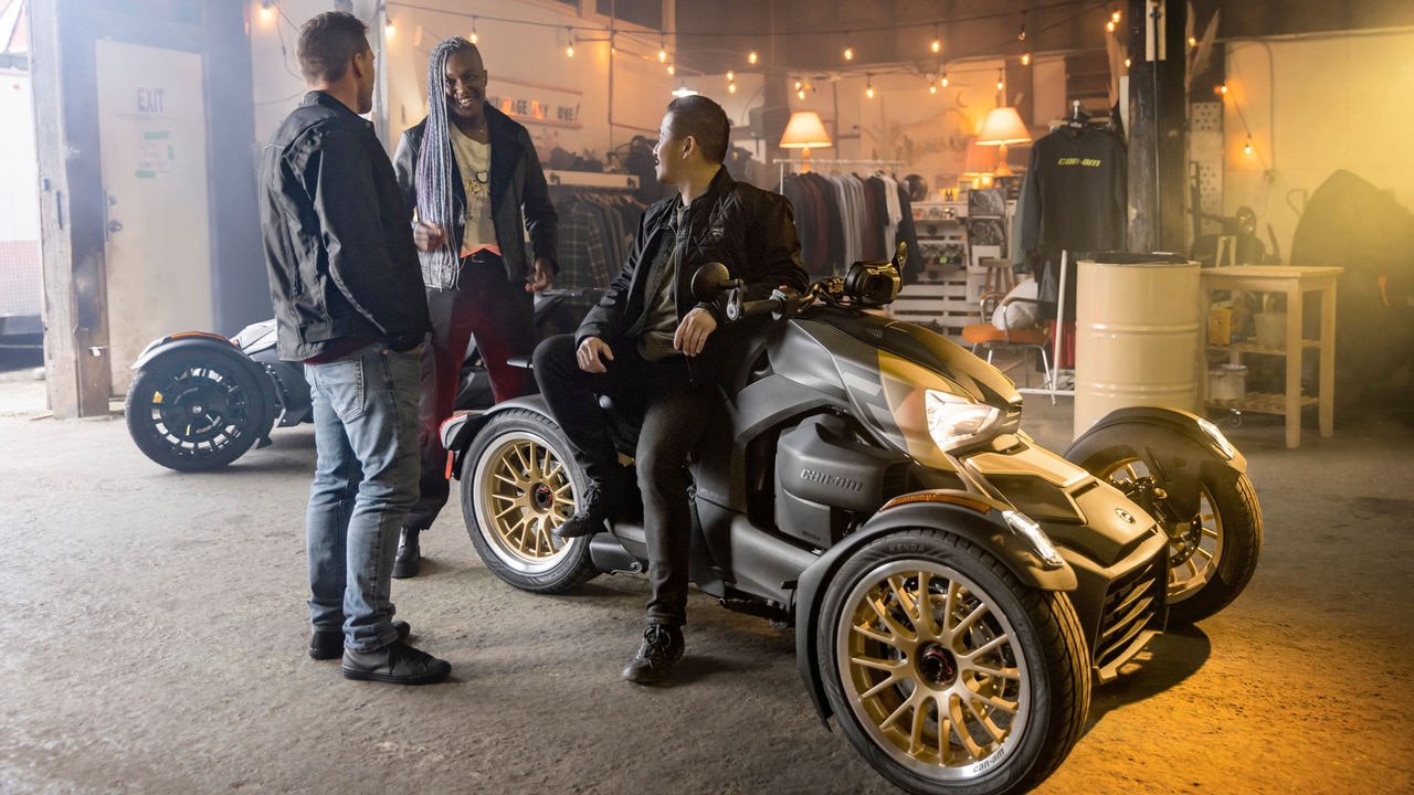 3 riders talking in a garage on a 2023 Can-Am Ryker