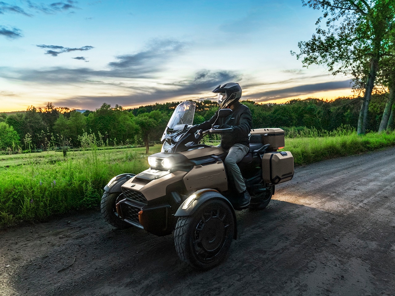 Rider sitting on a 2027 Can-Am Canyon in the countryside looking at the sunset