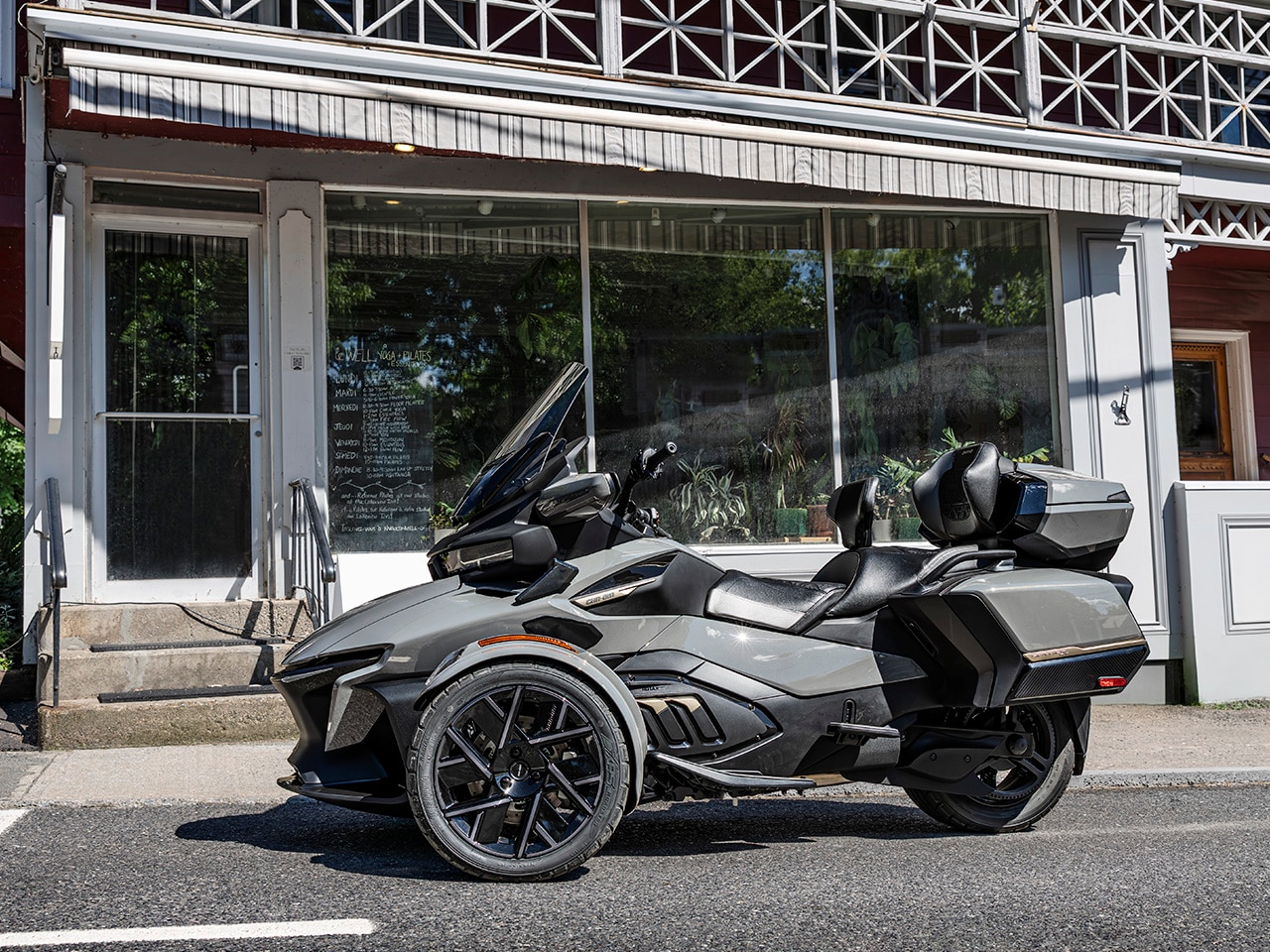 A Can-Am Spyder parked in front of a shop