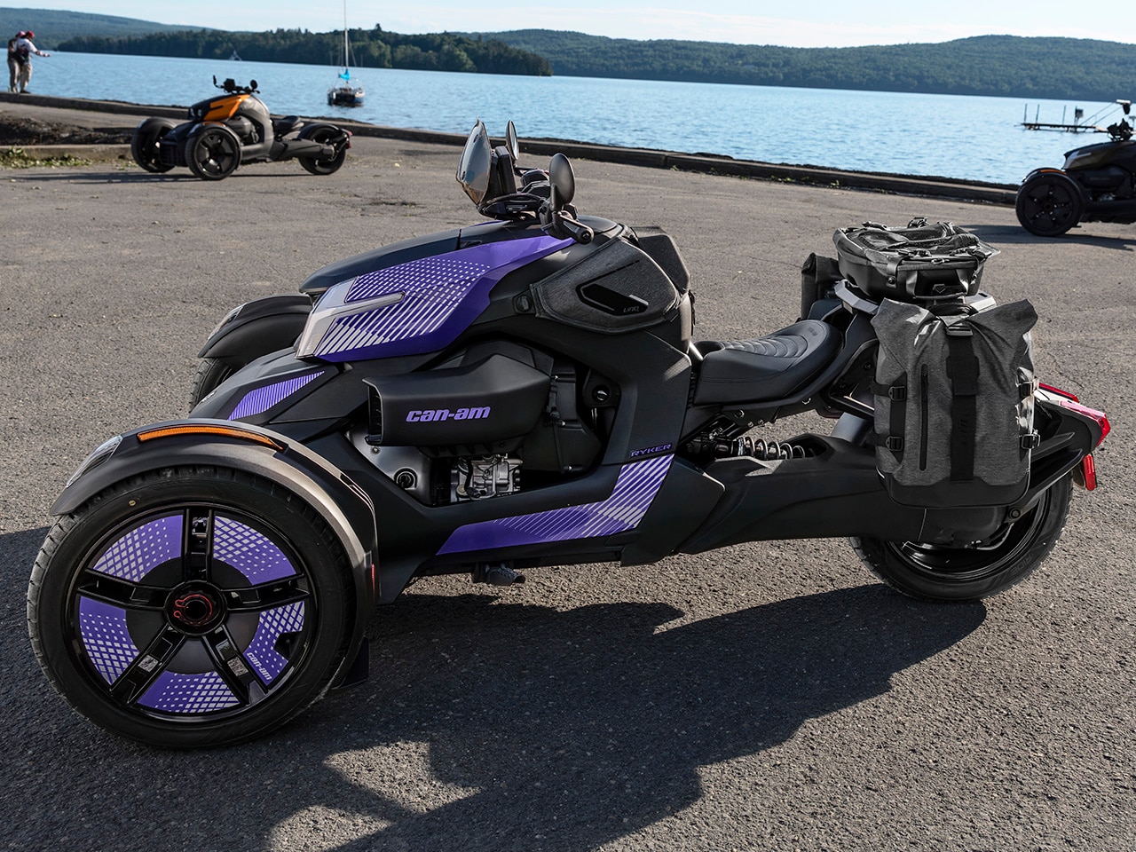 Several 2027 Can-Am Ryker 3-wheel vehicles parked near a lake