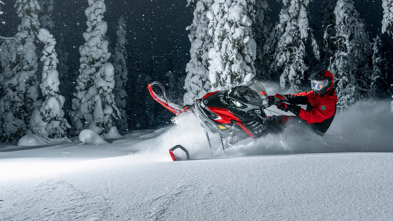 Lynx Xterrain RE snowmobile turning on deep snow in dark forest