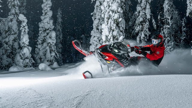 Lynx Xterrain RE snowmobile turning on deep snow in dark forest