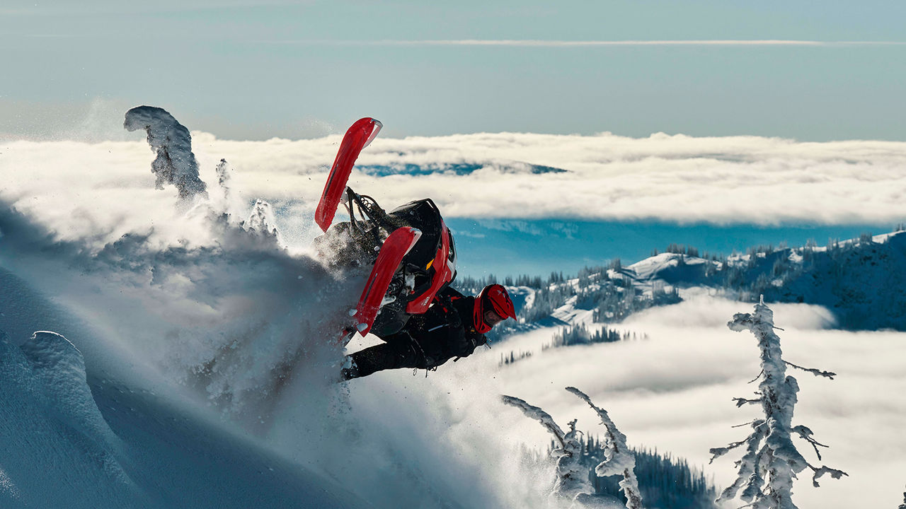 Lynx Shredder RE snowmobile making a turn in top of the mountain