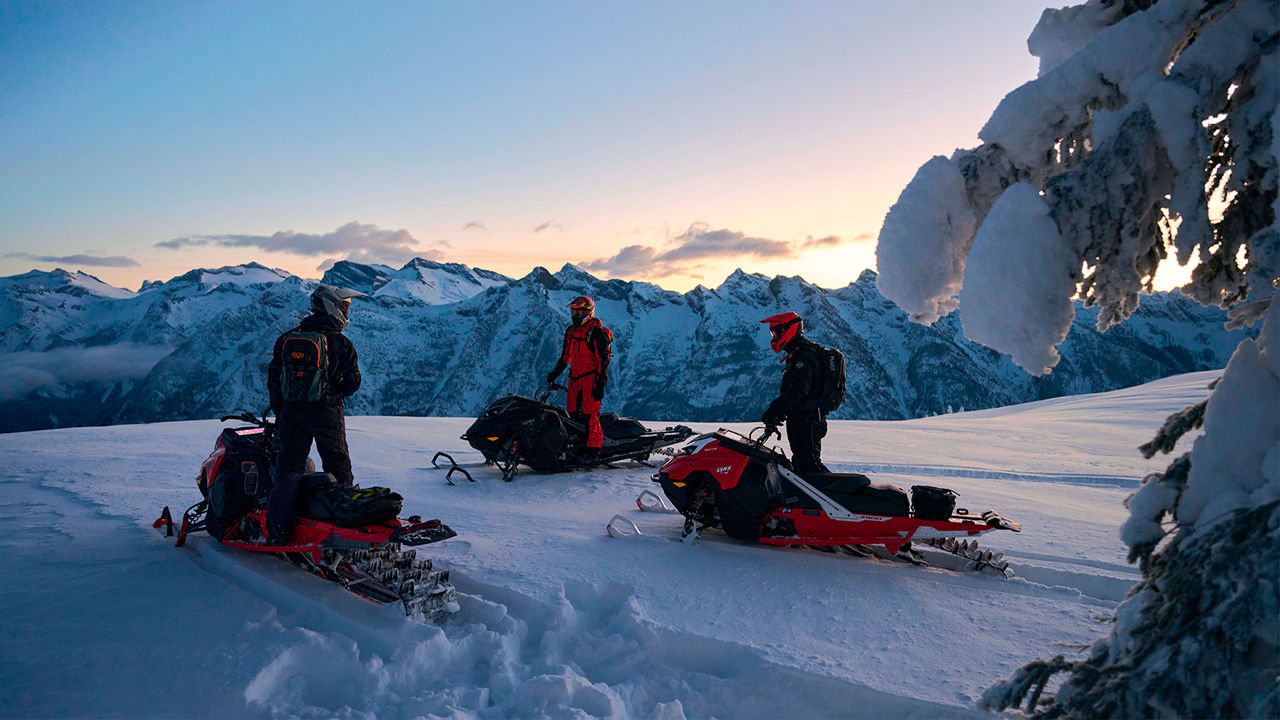 Lynx Shredder snowmobiles parked in the mountains at sunset