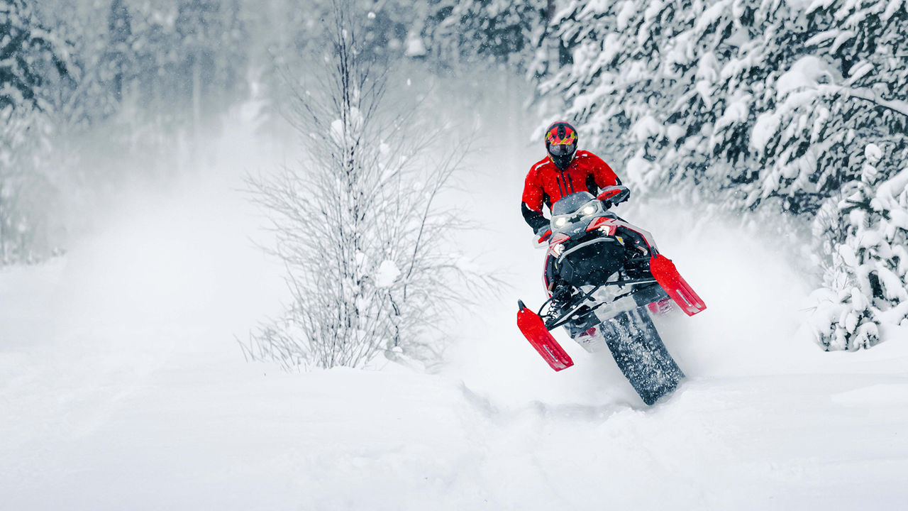 Rave RE snowmobile lifting skis from a bump on a trail