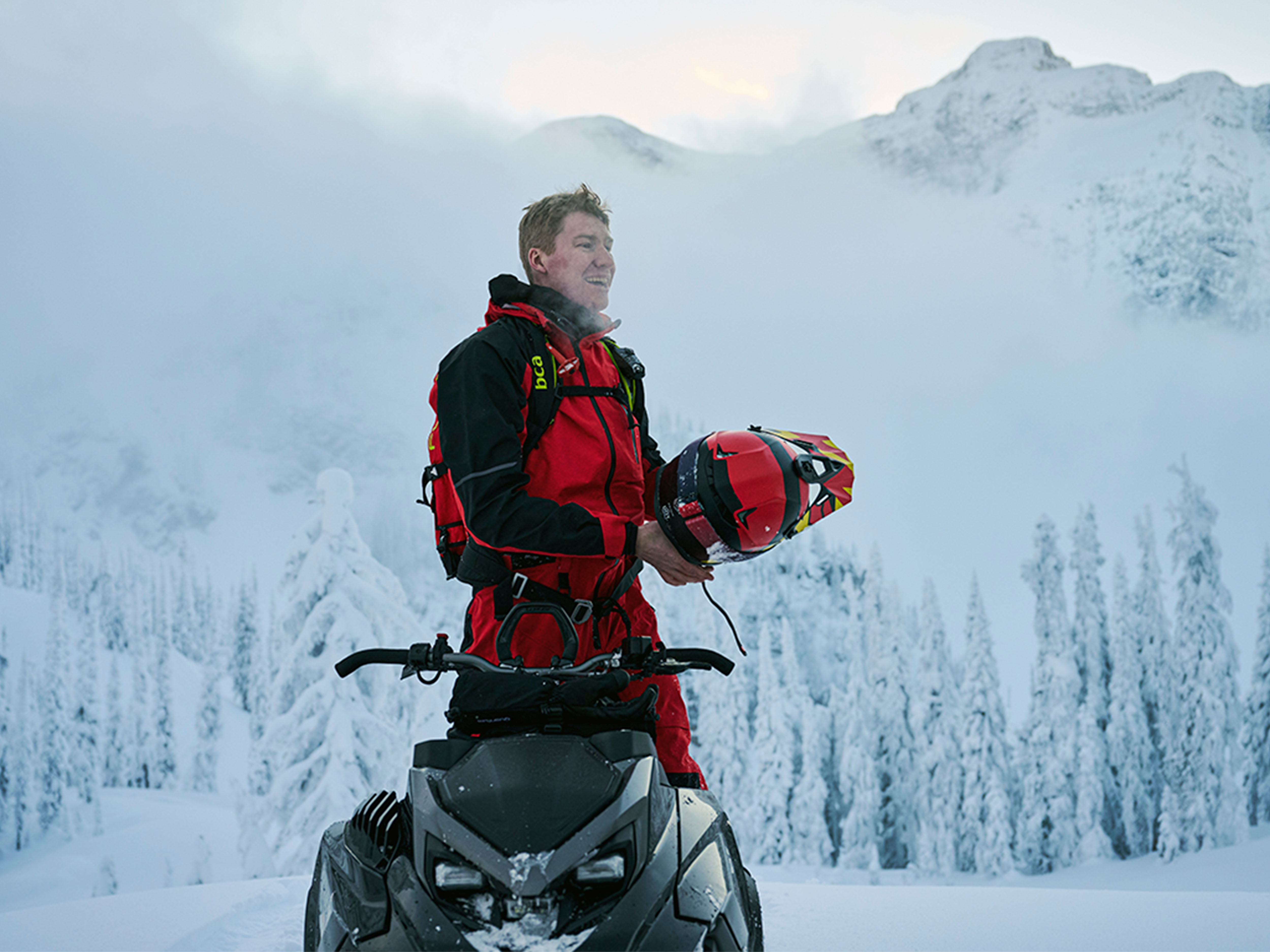 Rider taking his helmet off on a snowmobile