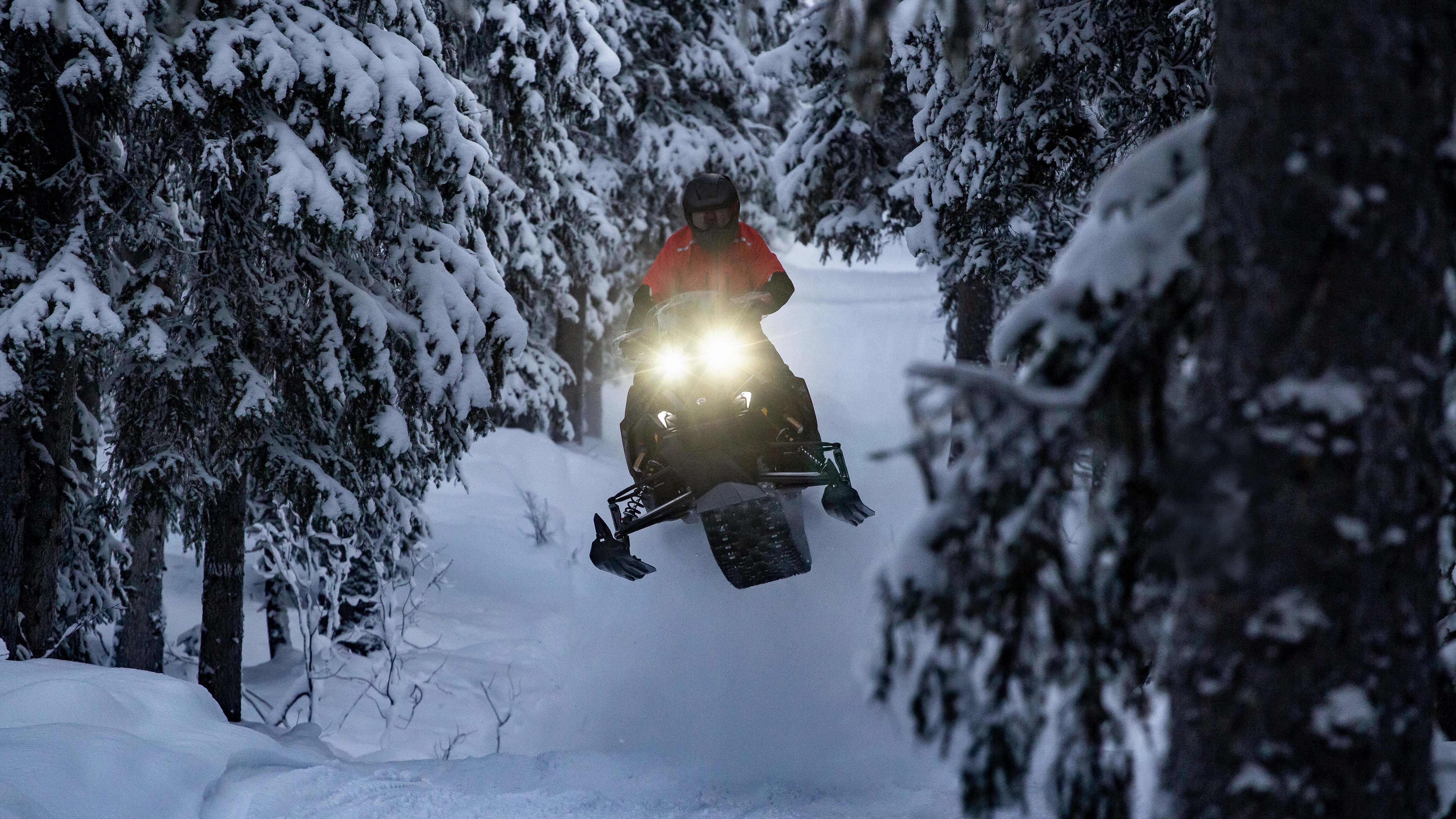 Lynx Rave RE 2026 snowmobile jumping on forest trail