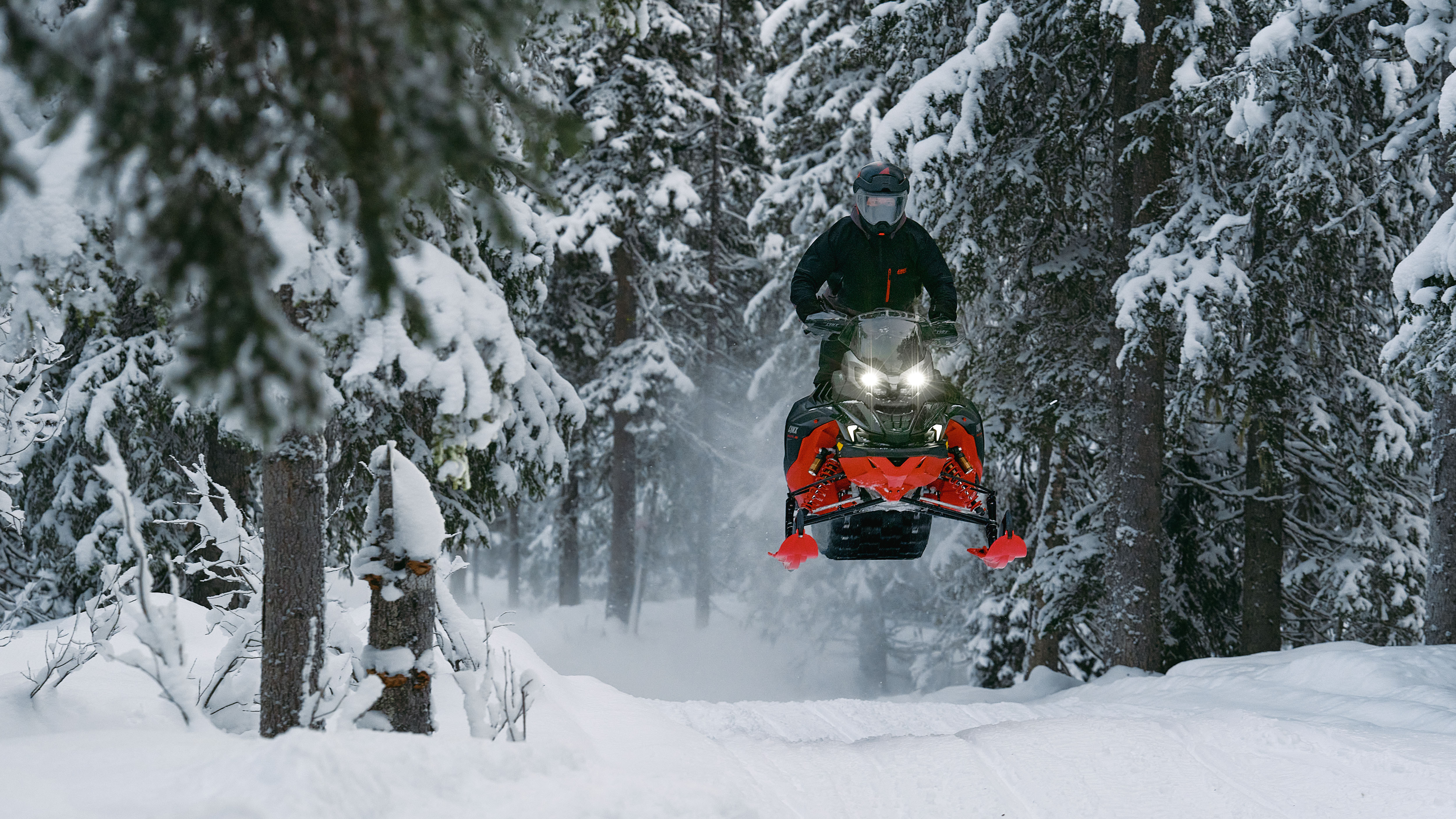 2026 Lynx Brutal RE snowmobile leaping over a bump on the trail.