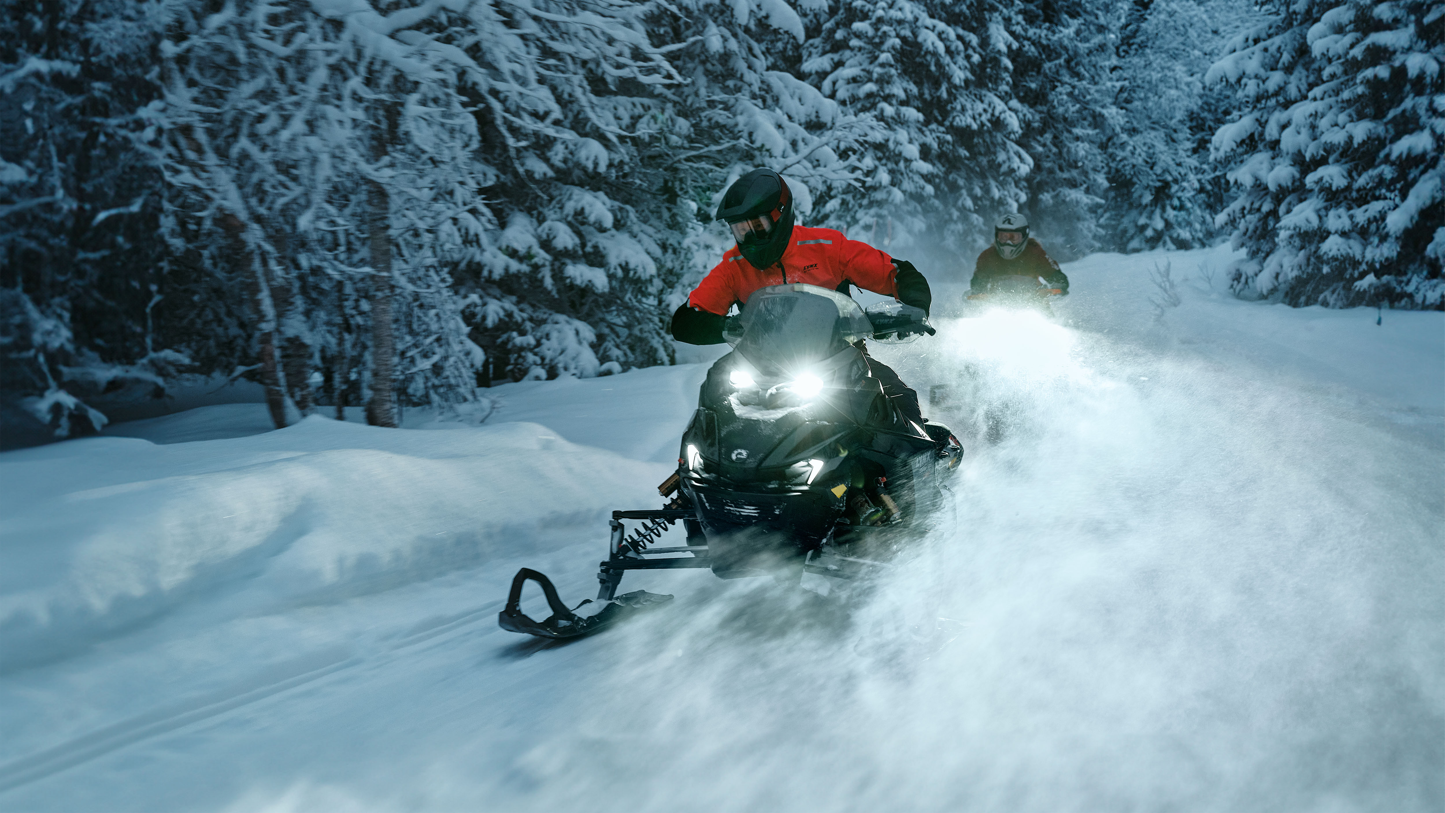 Two Lynx Rave RE 2026 snowmobiles riding fast on twisty trail 