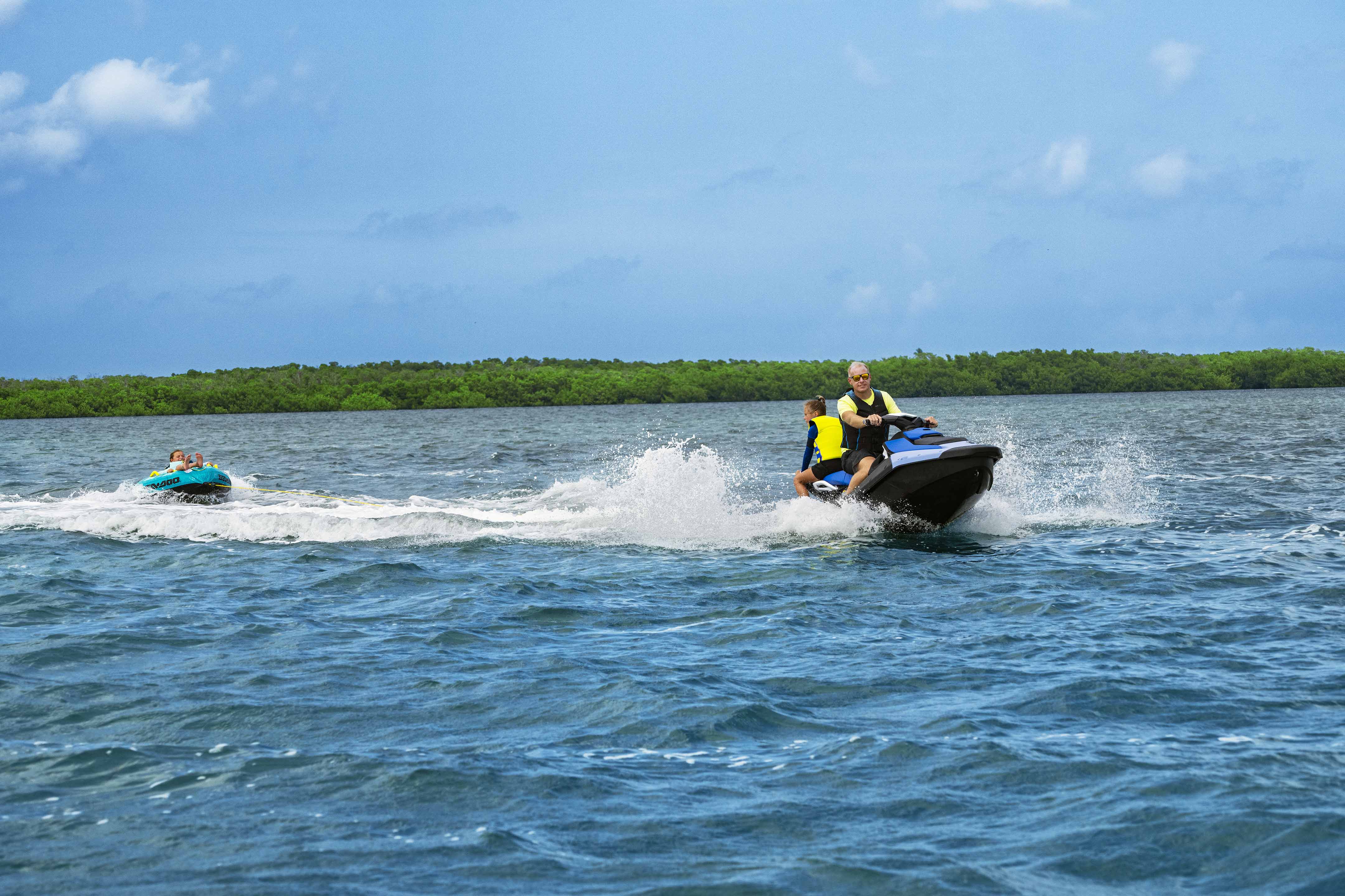 Dad and daughter on a Sea-Doo Spark 3UP personal watercraft pulling a tube