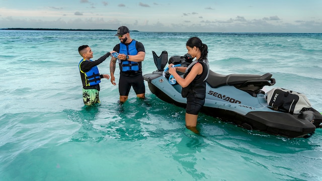Man and his two kids standing in the water next to a 2027 Sea-Doo Spark personal watercraft